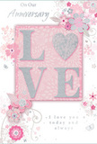 This anniversary card offers a gentle celebration of lasting romance, combining soft pastel pinks, silvery greys, and creamy whites to create an atmosphere of treasured intimacy, much like an evening stroll through the quiet streets of East Finchley. At the centre of the design sits the word LOVE, formed from softly raised letters dusted with fine glitter so that they glisten without overwhelming the eye. The letter O is artfully replaced by a shimmering heart shape, its silvered texture catching the light in a way that suggests the steady glow of a long-term relationship. Around this central emblem, delicate blooms unfurl in shades of blush and mauve, their petals painted with an almost watercolour softness that allows each flower to blend gently into the next. Fine, flowing lines describe slender stems and curling vines, adding a feeling of lightness and care, reminiscent of the way florists arrange anniversary bouquets for homes off Fortis Green or near East Finchley station. Tiny touches-scattered petals, swirling flourishes, and subtle butterfly silhouettes-bring a sense of movement and whimsy, like a garden just stirring to life in early spring. The background is washed in a gentle pink tone, calming and warm, which allows the silver details and floral outlines to stand out with quiet clarity. Above and below the motif, the phrases On Our Anniversary and I love you today and always appear in graceful script, conveying honest affection rather than showy sentiment. The entire composition feels like a keepsake of shared years and cherished memories, as tender and thoughtfully composed as a hand-delivered anniversary bouquet from a trusted East Finchley florist.